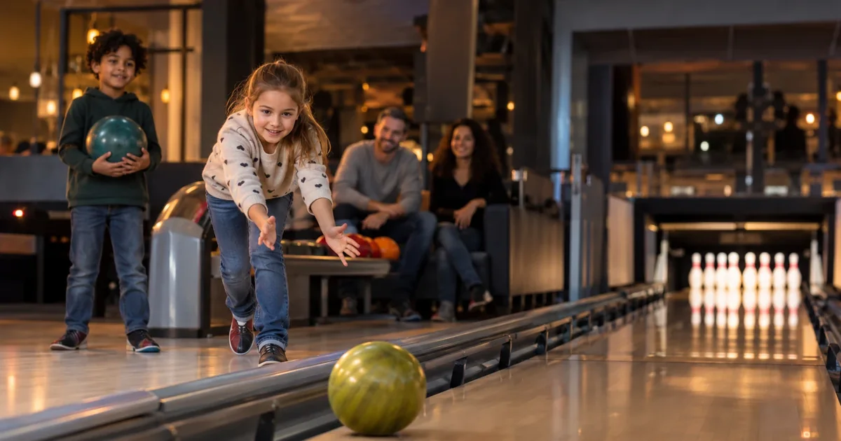 Ein Kind rollt eine Bowlingkugel auf einer Bahn mit hochgestellten Banden.