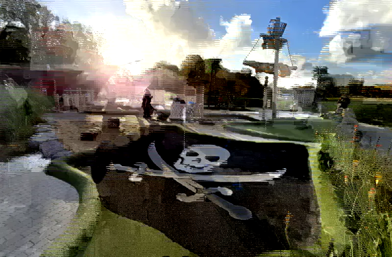 Piratenbahn mit Totenkopf-Motiv und Schiffsmast bei Pirate’s Island Adventure Golf